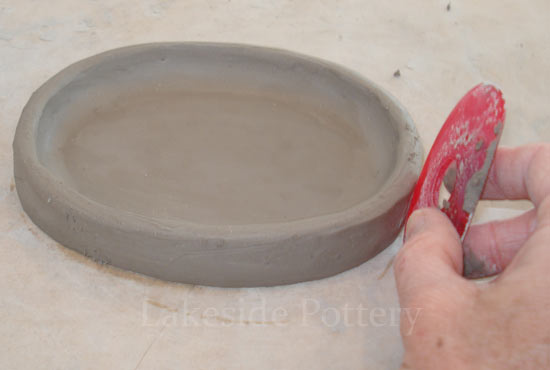 using a silicone rib to smooth pot's walls