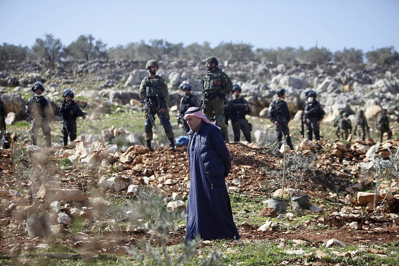 Israeli soldiers and a Palestinian man in the West Bank